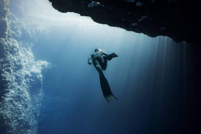 Freediver swimming under the blue hole arch