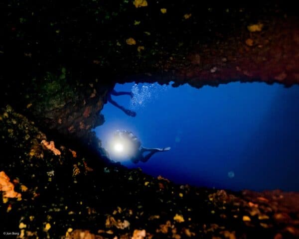 SCUBA diver flashing light through the double arch