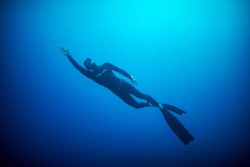 Freediver with arm above head surfacing