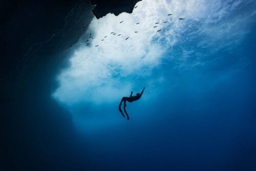 Distant freediver heading towards the surface