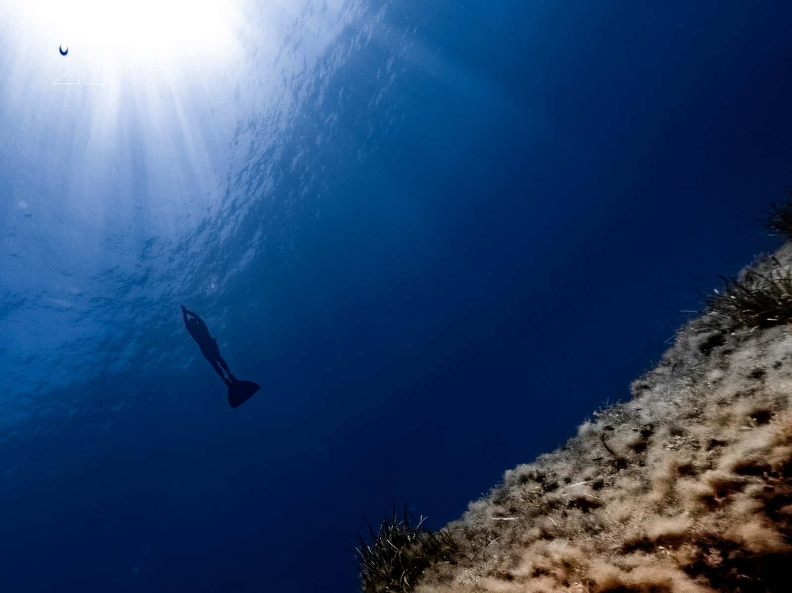 Freediver with mono-fin swims towards surface