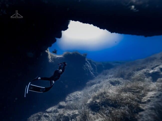 Freediver swims towards arch