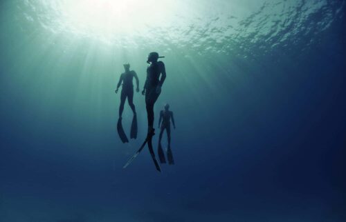 Three freedivers ascending from depth
