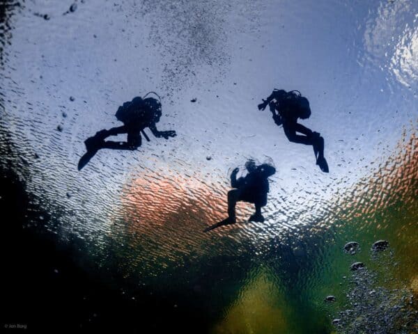 Three SCUBA divers on the surface of Blue hole