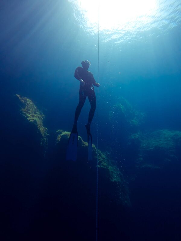 Freediver ascending on a line towards light