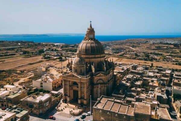 Drone shot of large church in Gozo with the sea in the background