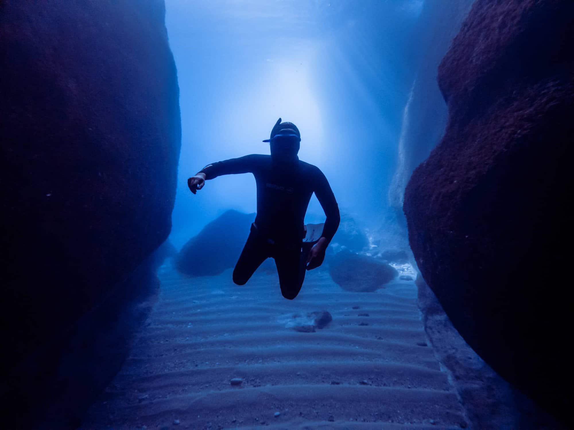 Freediver levitating between two large rocks