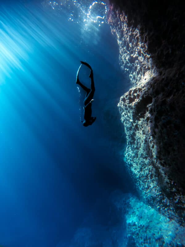 Freediver descends in open cave by wall