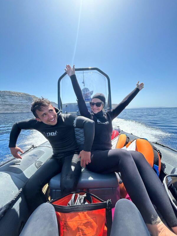 Two freedivers on our RIB, with one of them with their hands int he sky, smiling!